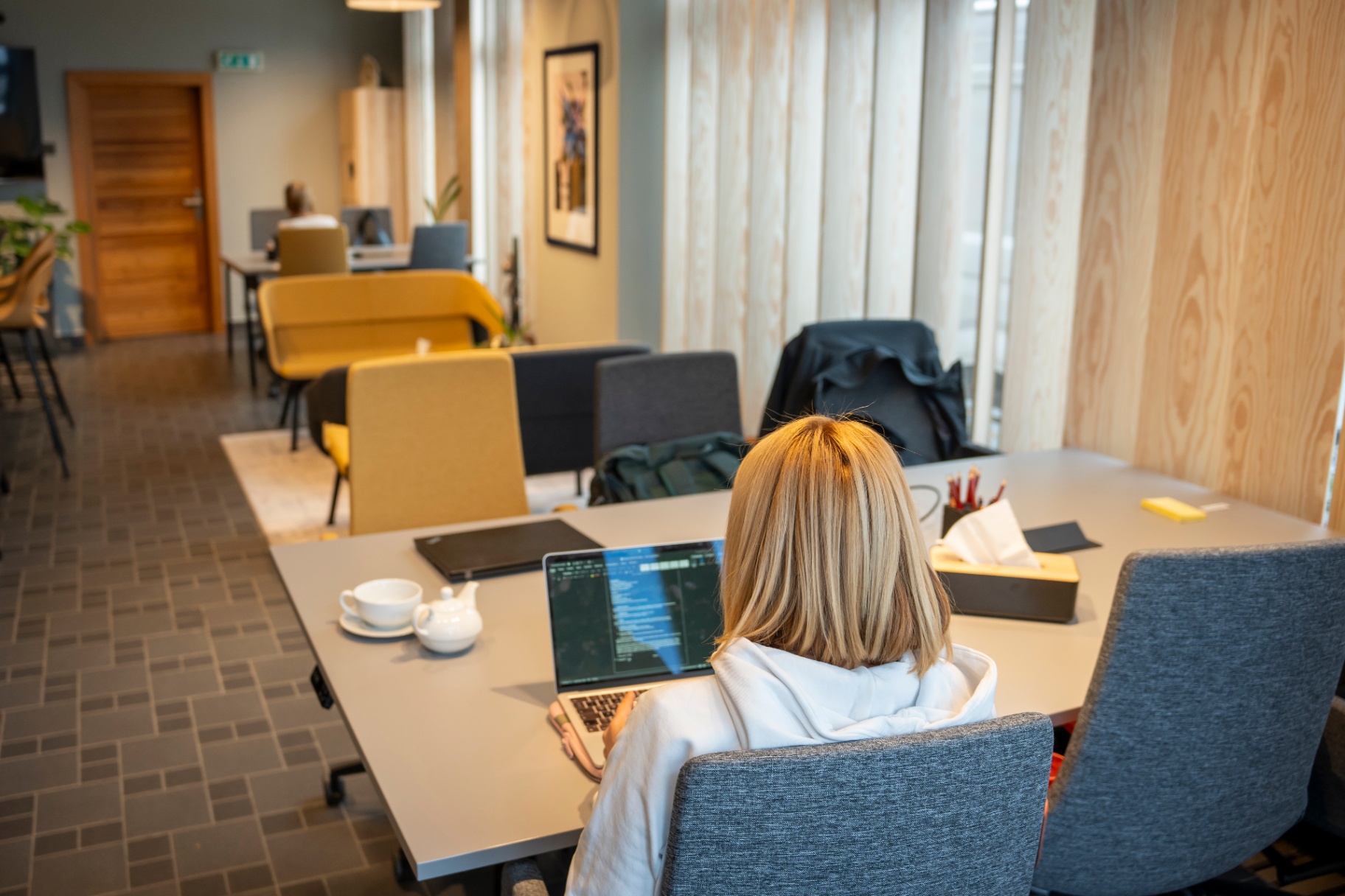Brandová fotografie coworkingu — žena pracující u stolu v moderní kanceláři