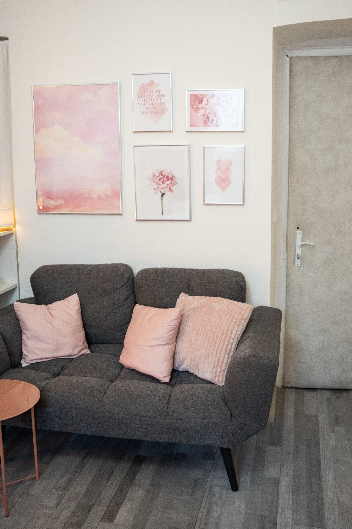 Zákaznický koutek salonu s pohovkou a galerií růžových obrazů
