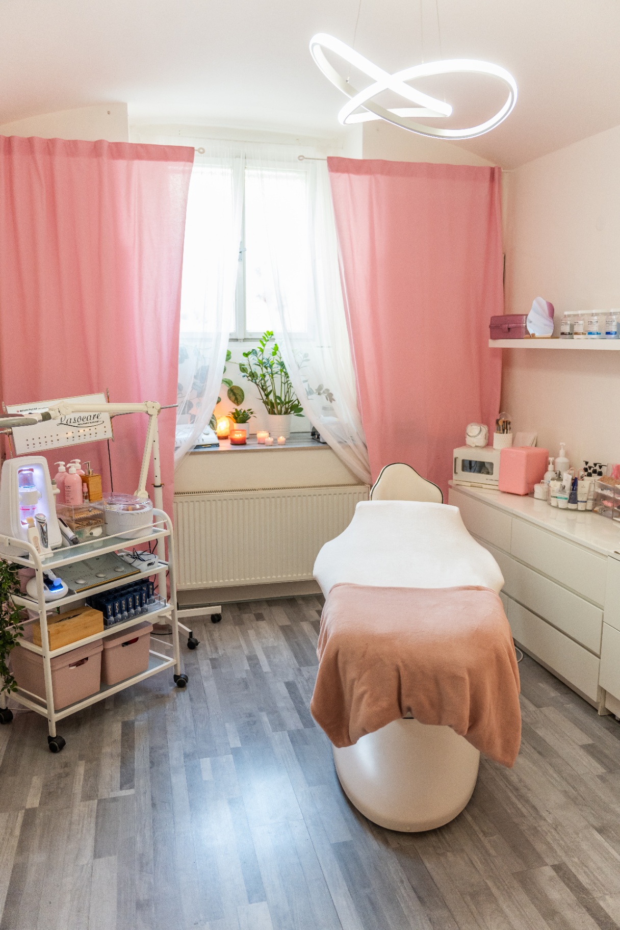 Ošetřovací místnost salonu Moje beauty dobrodružství s růžovými závěsy a designovým svítidlem