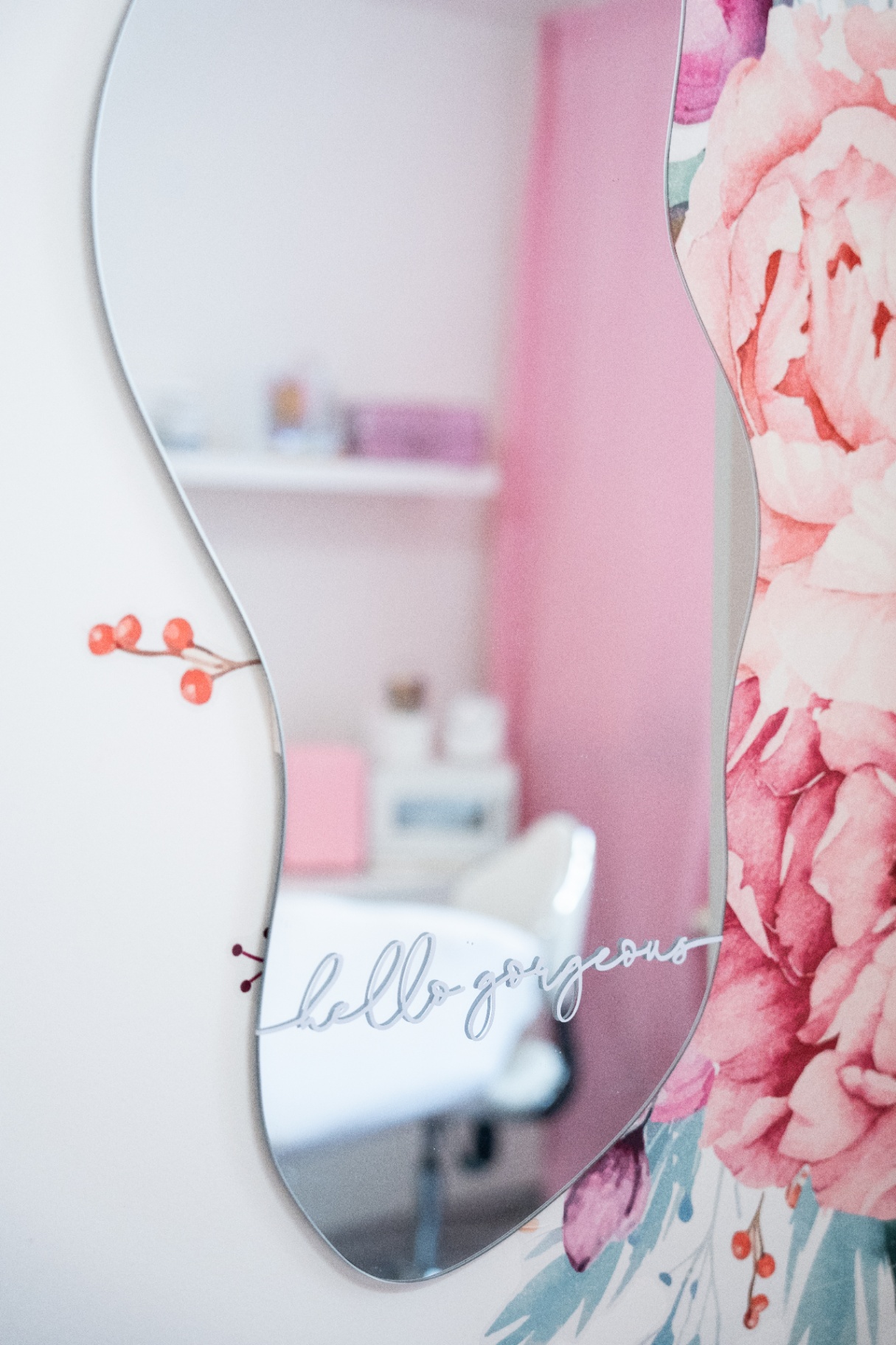 Detail zrcadla s nápisem hello gorgeous a květinovou tapetou v salonu
